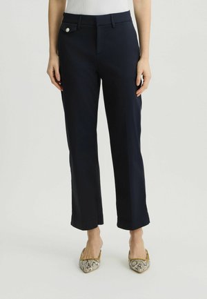 Pantalons taillés bleu marine avec un devant plat, jambes droites et un détail en bouton argenté brillant à la taille. Texture de tissu uni.
