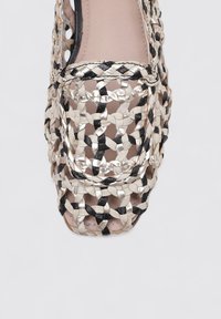 Sandalias trenzadas que presentan una mezcla de hilos en beige, negro y metálico en un diseño abierto, con un forro interior suave y punta redondeada.