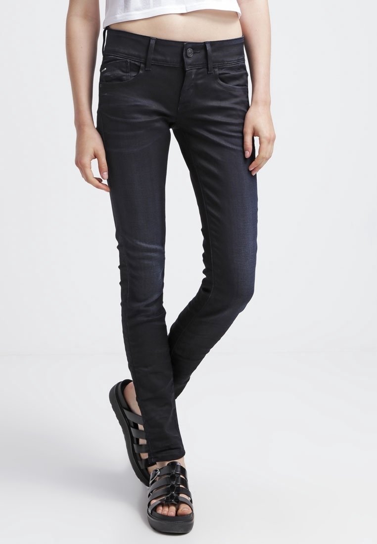 Svarta slim-fit jeans med en jämn textur, diskreta framfickor och en funktionell midja med en knapp. Bärs med svarta sandaler.