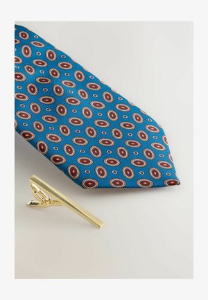Blue tie with oval patterns in red and white; accompanied by a shiny gold tie clip with a rectangular shape and a clasp mechanism.