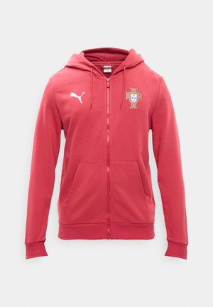 Hanorac roșu cu fermoar, cu buzunare frontale, emblemă a echipei naționale de fotbal a Portugaliei pe partea stângă a pieptului și logo Puma alb pe partea dreaptă a pieptului.