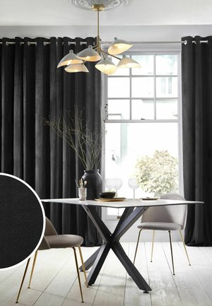Essbereich mit schwarzen Samtvorhängen, modernem schwarzen Esstisch, beigen Stühlen mit goldenen Beinen, einer schwarzen Vase mit Zweigen und einem Kronleuchter an der Decke.