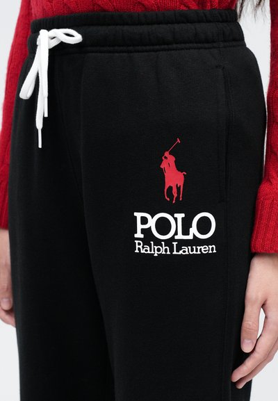 Čierne tepláky vyrobené z bavlny s elastickým pásom, s bielym šnúrkou, červeným logom a bielym textom "POLO Ralph Lauren."