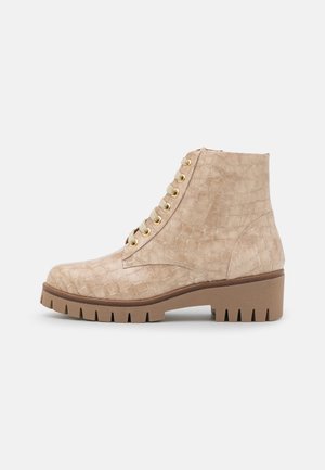Bota beige hasta el tobillo con textura de cocodrilo, cordones en la parte frontal, ojales dorados y suela gruesa de tacos con tacón cuadrado.