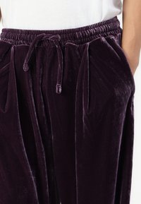 Sammetspajama byxor i djup lila, med resårmidja och dragsnodd, sidofickor och mjukt, slätt material.