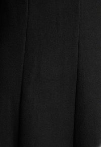 Czarna dzianina z delikatnymi pionowymi plisami i drobną prążkowaną teksturą.