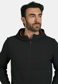 Felpa con zip nera, dal design aderente, con una foderatura interna arancione a contrasto e tasche laterali con zip. Tessuto dalla superficie liscia.