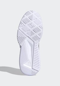 Witte zool van een sportschoen met een gestructureerd profiel, voorzien van richels en groeven voor grip. Logo is zichtbaar nabij de hiel.