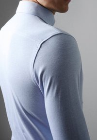 Lichtblauw overhemd met lange mouwen en een kraag, gemaakt van een gladde stof. Heeft een fitted ontwerp met schoudernaden en minimale textuur.