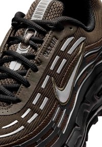 Καφέ και μαύρο αθλητικό παπούτσι Nike Max Air 2006 με υφασμάτινο δίχτυ, μαύρα κορδόνια και αντανακλαστικές ασημένιες λεπτομέρειες σε κοντινή λήψη.