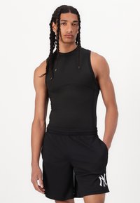 Top deportivo negro sin mangas con un diseño ajustado, combinado con shorts negros que presentan un logo blanco en la pierna izquierda. Textura suave en toda la prenda.