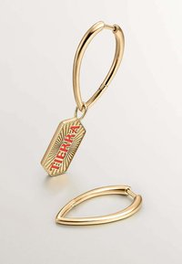 Los pendientes de aro dorados presentan un charm rectangular con el texto en relieve "TIERRA" y un diseño de rayos de sol. Superficies metálicas suaves con acabado brillante.