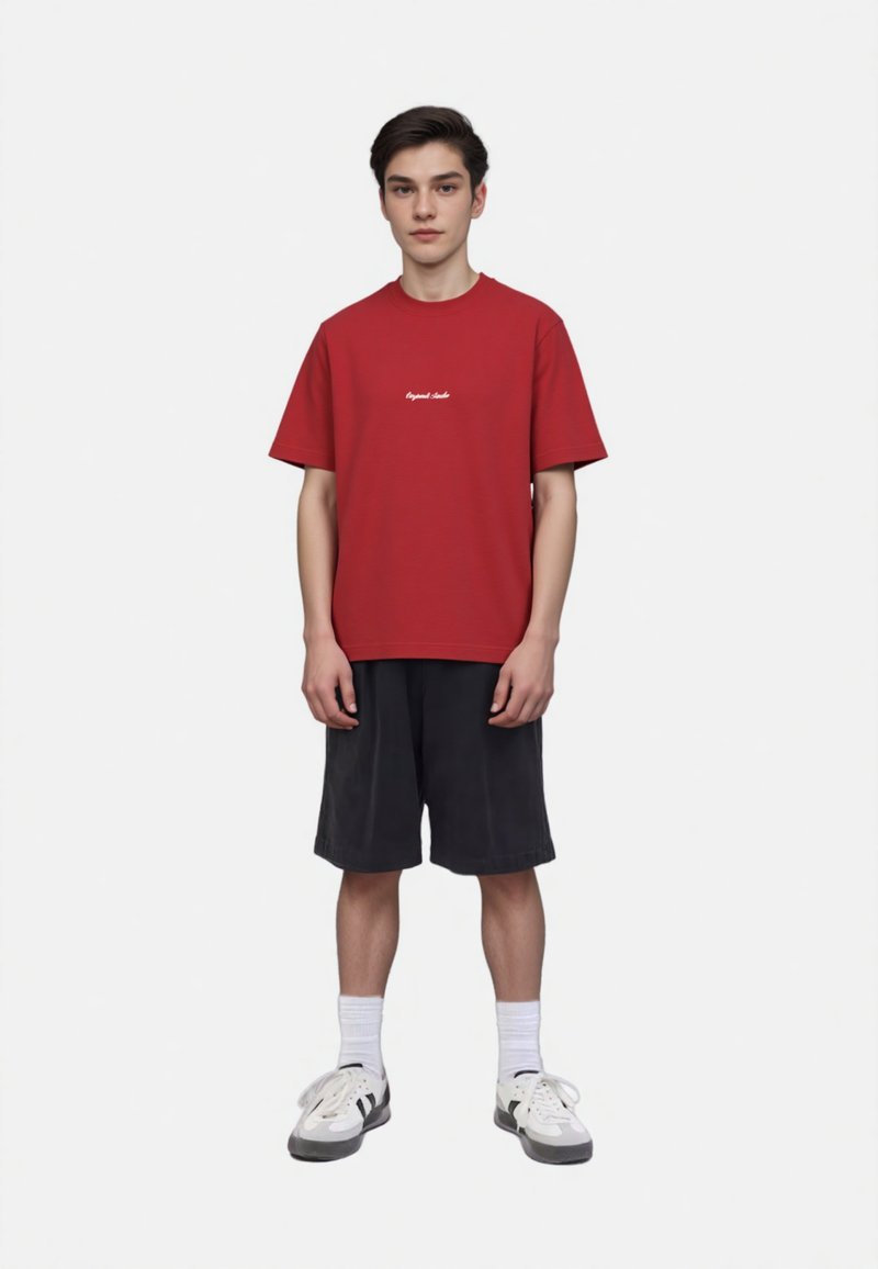 Red crew-neck t-shirt with short sleeves and white text. Paired with black shorts, white socks, and gray sneakers with black accents.