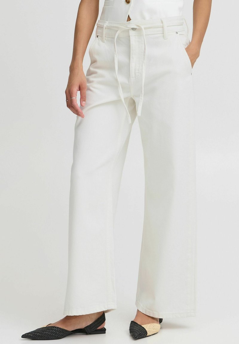 Pantalones anchos blancos con cintura ajustable, fabricados en un material ligero. Presentan bolsillos frontales y un diseño texturizado.