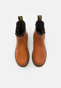 Brązowe skórzane botki do kostki z czarnym futerkiem, żółtymi przeszyciami i czarną pętelką z tyłu. Okrągły nosek.