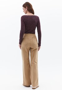 Tan brede broek met hoge taille en zakken, gecombineerd met een donker bordeaux lange mouw top. Glad stof, eenvoudig ontwerp, casual pasvorm.