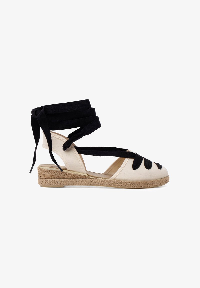 Kreemivärviline espadrille-kork, mustade kangast paeltega. Omab jute-kattega tallat ja avatud disaini varvaste juures. Lame konts.