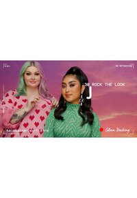 Due persone sono in piedi contro uno sfondo rosa sfumato. La persona a sinistra indossa un maglione rosa con cuori rossi; la persona a destra indossa un top verde textures.
