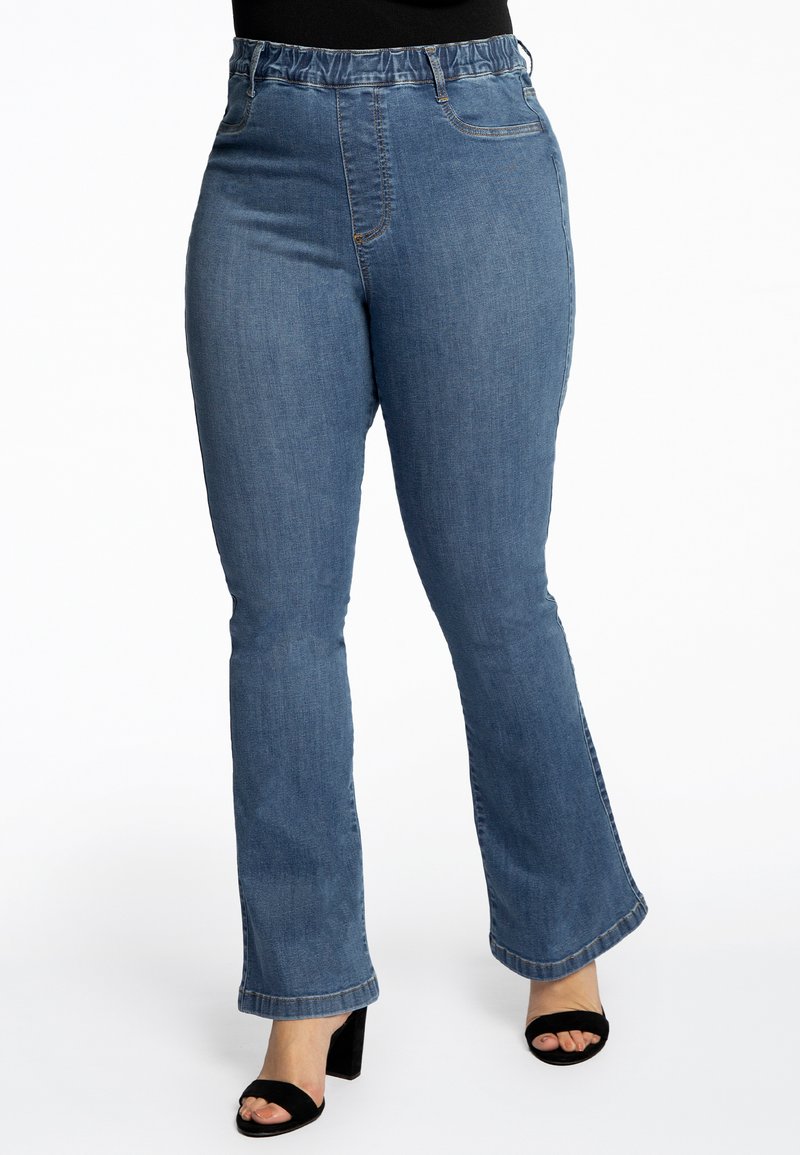 Jean en denim bleu évasé avec une taille élastique et des poches avant, présentant une texture lisse et une finition délavée.