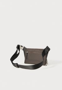 Grå stoff crossbody-veske med justerbar svart reim, frontglidelås-lomme og sølvfarget hardware-detaljer. Glatt tekstur, kompakt form.
