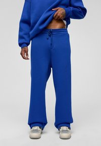 Blauwe oversized sweatshirt en bijpassende joggingsbroek in een effen kleur, gemaakt van zachte stof; losse pasvorm met een elastische tailleband en een trekkoord.