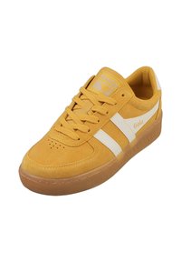 Zapatillas de ante amarillo con rayas y logotipo blancos, que cuentan con un cuello acolchado y una suela de goma texturizada. Punta perforada para ventilación.