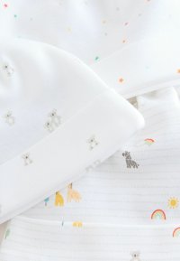 Bonnet et couverture pour bébé blancs avec des motifs de petits ours gris clair, des étoiles colorées et des illustrations d'animaux joyeux, avec des détails d'arc-en-ciel et de soleil.