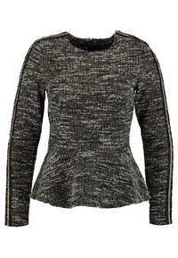 Maglione a maniche lunghe in bianco e nero con trama, orlo a peplo e dettagli in catena metallica lungo le maniche. Scollo rotondo.