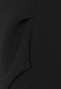 Svart kläde med en jämn textur som har ett lagerdesign på ena sidan. Inga synliga mönster eller detaljer.