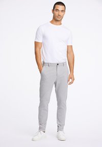 Un pantalon de jogging gris avec une coupe décontractée, doté de poches latérales et d'une fermeture à bouton, associé à un t-shirt blanc uni et des baskets blanches.