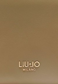 Barna bőr felület texturált kivitelben. Aranyszínű, dombornyomott "LIU•JO MILANO" logóval. Egyszerű, elegáns dizájn.