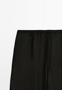 Black skirt with an elastic waistband and a drawstring, shown against a plain white background. No visible patterns or embellishments.