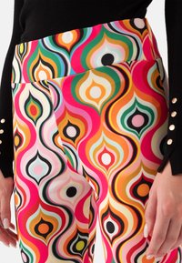 Kleurige, gemusterde legging met een hoge tailleband, voorzien van een retro ontwerp in roze, oranje, groen en zwarte druppelvormige figuren. Glad materiaal.