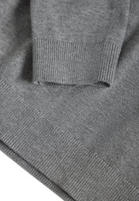 Gros plan sur la manche et l'ourlet d'un pull gris en maille montrant des poignets côtelés fins et une texture douce en laine.