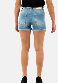 Lichtblauwe denimshorts met een aansluitende pasvorm, omgeslagen zomen en twee achterzakken. Kenmerkt zich door een contrasterende band op de tailleband.