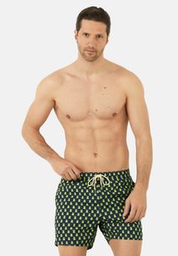 Costumi da bagno da uomo di colore navy con un motivo di piccole rane verdi. Presentano un elastico in vita con una corda di regolazione beige per una vestibilità regolabile.
