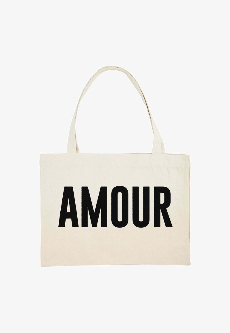 Stoffen tote bag in crème met het woord "AMOUR" prominent gedrukt in vette zwarte letters. Twee stevige handvatten voor het dragen.