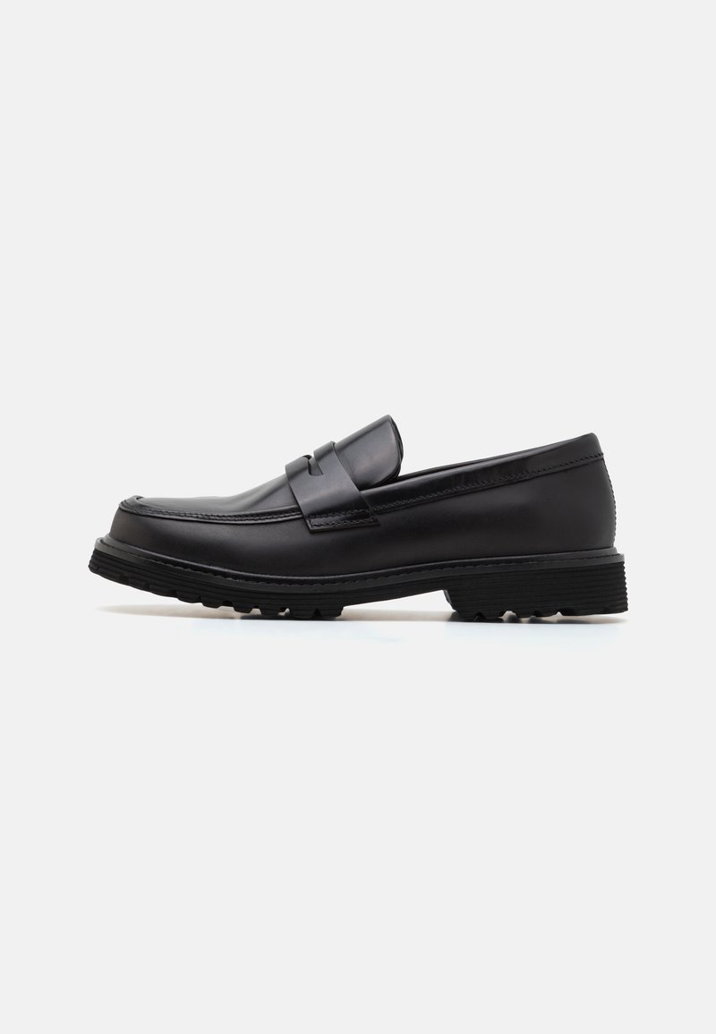 Schwarze Leder-Loafer mit runder Zehenform, dekorativem Riemen und strukturiertem Gummisohle. Glatte Oberfläche mit minimalen Details.