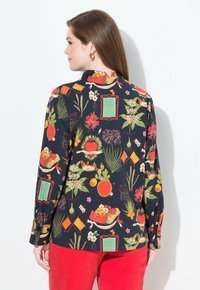 Blusa a maniche lunghe in tessuto blu navy scuro, caratterizzata da una vivace stampa floreale e di frutta, con dettagli in rosso e verde, e una vestibilità comoda.