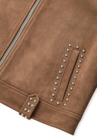 Veste en suédine marron avec fermeture éclair argentée, accents cloués sur le côté, texture lisse et détail de poche plate.