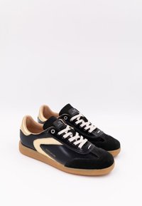 Svarta och guldiga sneakers i läder och mocka med en böjd design, beige snören och en texturerad gummisula. Logotypen är tydligt synlig.