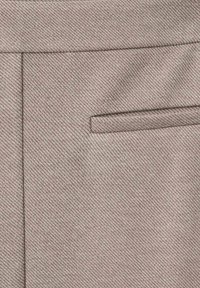 Pantalones de un beige claro con un patrón de espiga texturizado, que presentan un bolsillo plano en el lateral y un acabado de tela suave.