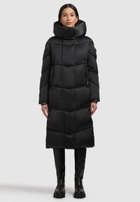 Schwarzer, gepolsterter Mantel mit hohem Kragen und geometrischem Steppmuster; verfügt über seitliche Reißverschlusstaschen und einen knielangen Schnitt.