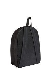 Zaino nero con forma arrotondata, superficie texturizzata e dettagli lucidi. Presenta spallacci imbottiti e una maniglia superiore per il trasporto.