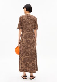 Brown tie-dye maxi dress made of soft fabric, featuring short sleeves and a relaxed fit, paired with an orange cap in hand.