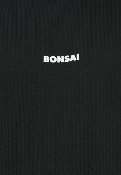 Zwarte t-shirt met ribbelstructuur met het woord "BONSAI" in vette, witte letters gecentreerd op de borst.