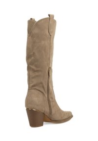 Bota alta hasta la rodilla de ante color canela, con punta puntiaguda, cremallera lateral y un tacón marrón apilado con ranuras horizontales. Textura suave, diseño minimalista.