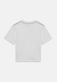 Hvit kortermet t-skjorte laget av bomull, med rund hals og kontrasterende detaljer langs skuldrene. Jevn tekstur, minimal design.