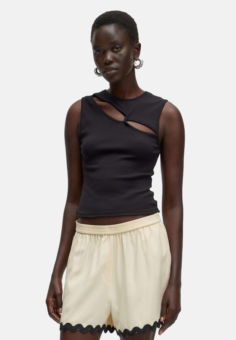 Zwarte geribbelde tanktop met uitsnijding aan de voorkant, gecombineerd met crème shorts met een gegolfde zoom en een elastische tailleband.