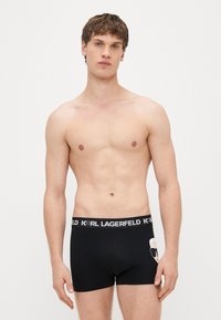 Melni bokseršorti ar logo jostu, uz kuras rakstīts “KARL LAGERFELD” un ir rakstura dizains. Izgatavoti no elastīga kokvilnas materiāla.